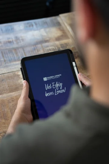 Person hält ein Tablet mit der Aufschrift „Viel Erfolg beim Lernen!“